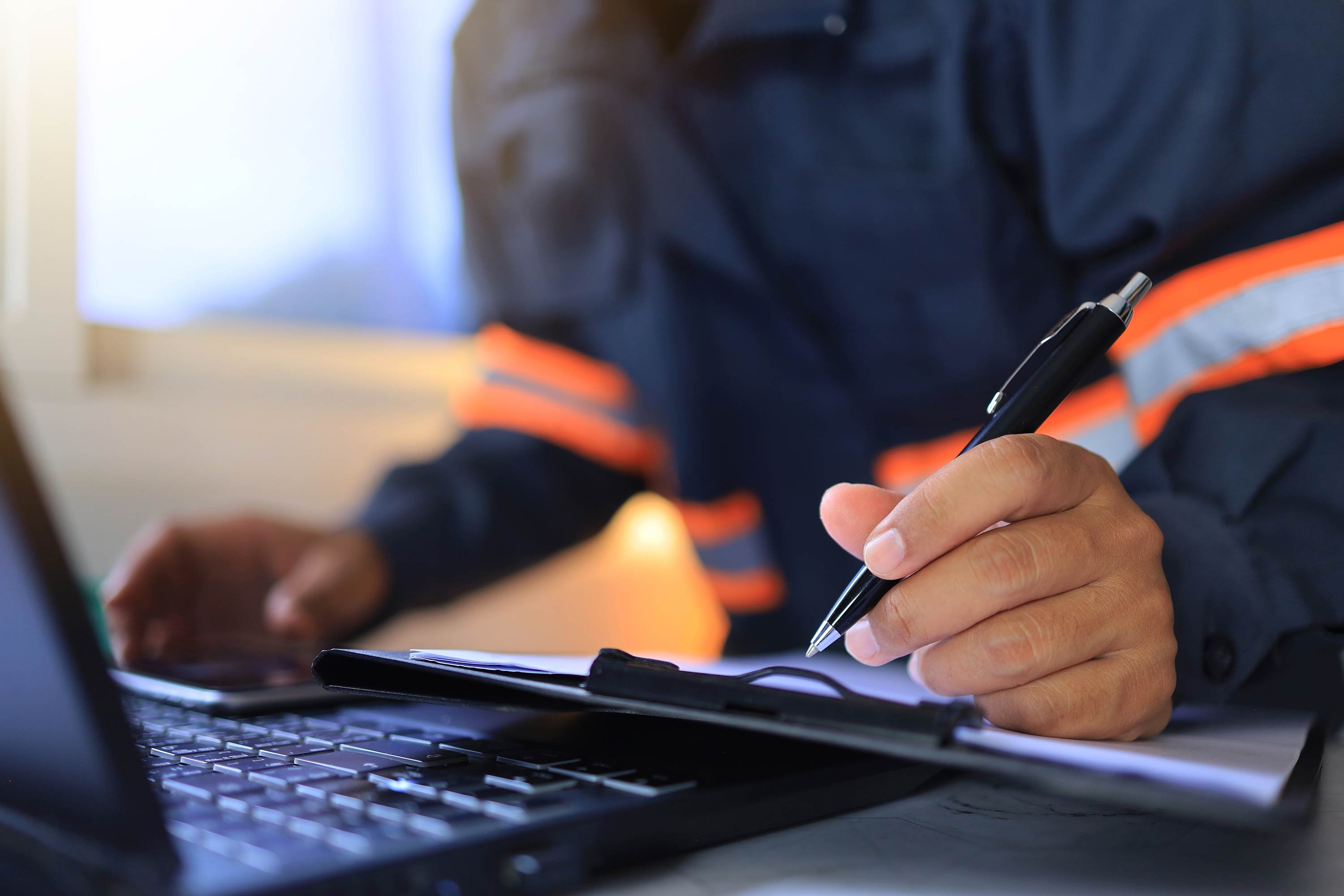 Person skriver trygghetscertifikat på papper med en dator framför sig