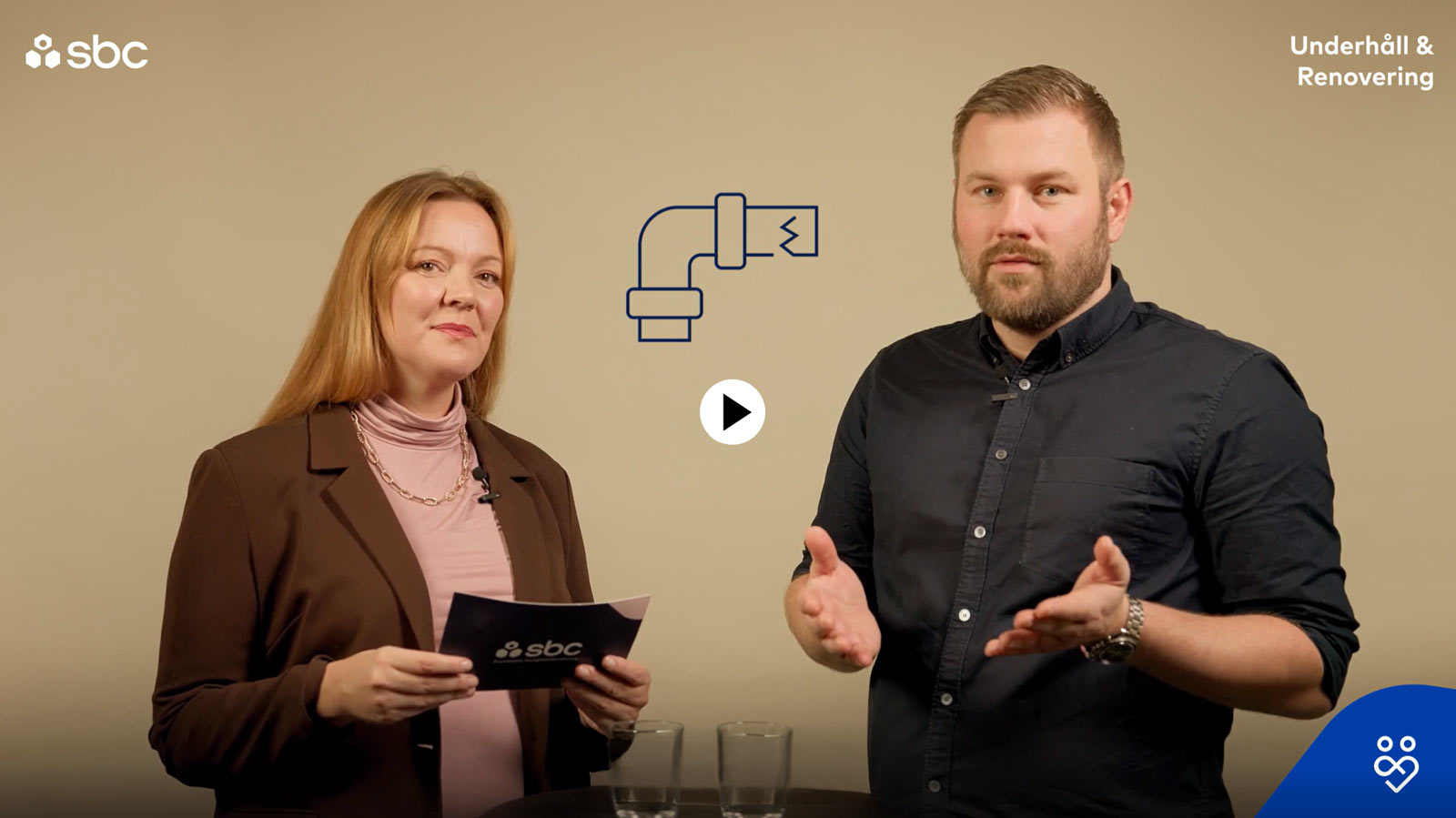 En man och en kvinna står i en studio och samtalar om vad man ska tänka på inför ett stambyte i en brf.