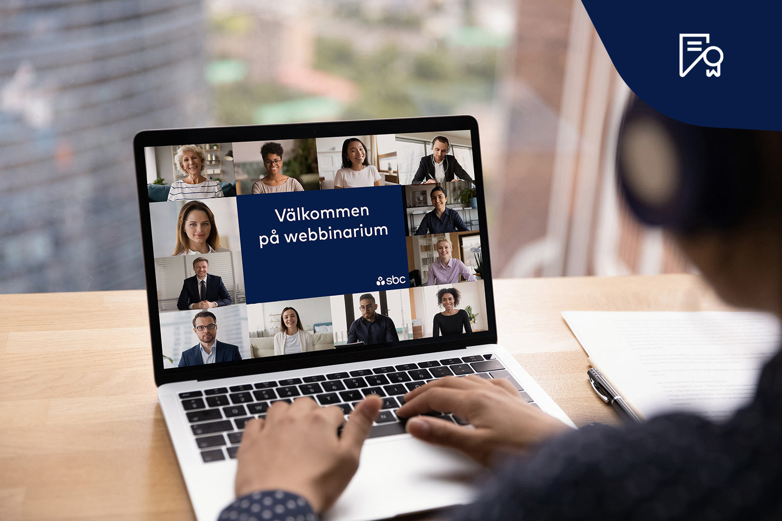 händer håller över tangentbordet med en skärm som visar webbinarium