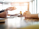 Förhandling mellan två jurister sker över ett skrivbord