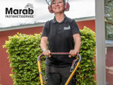Kvinnlig fastighetsskötare som klipper gräs