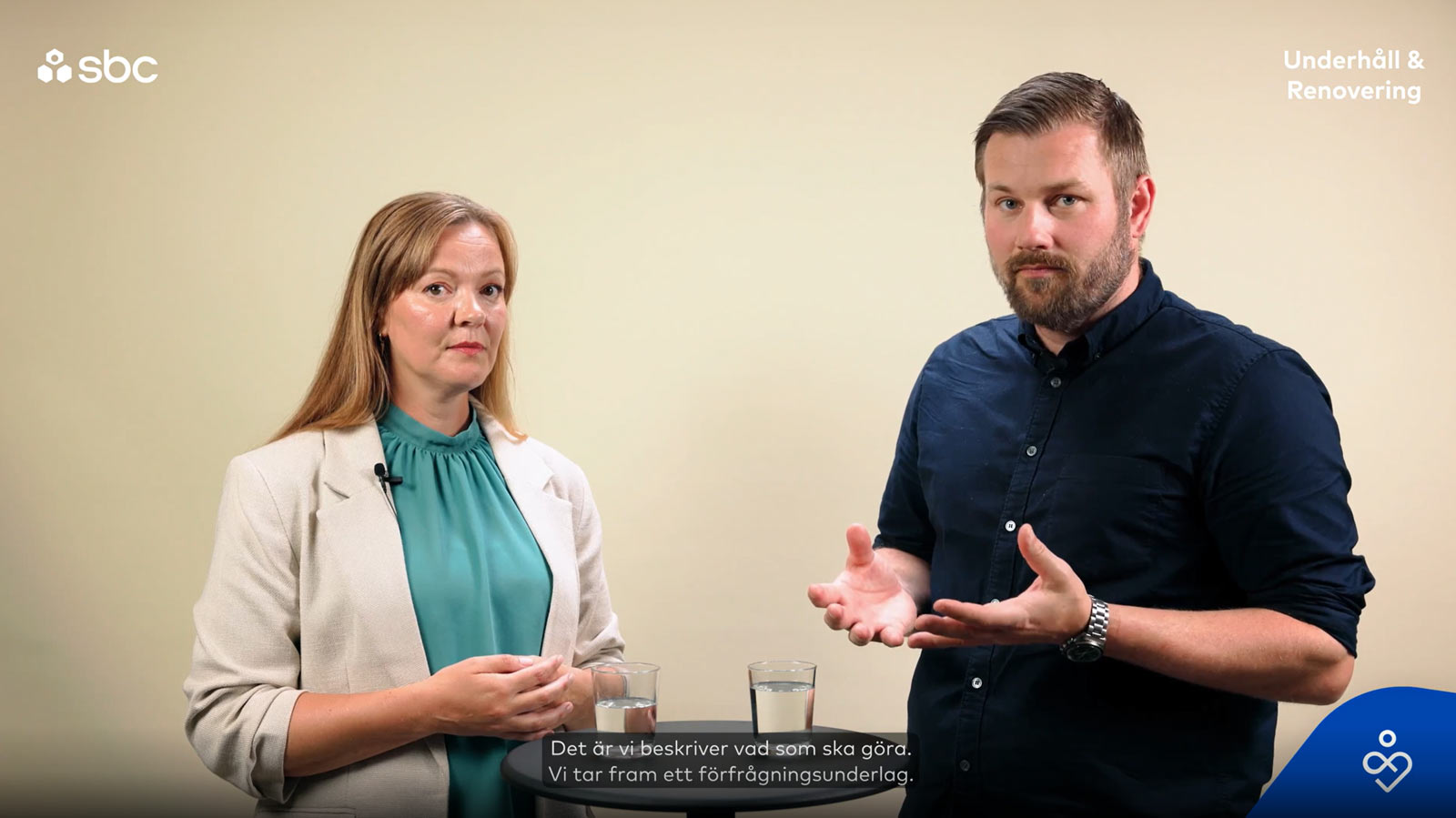 En man och en kvinna står i en studio och samtalar om hur en projektledare avlastar styrelsen i en brf.