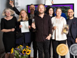 Medarbetare på SBC och externa konsulter håller upp pokaler och diplom