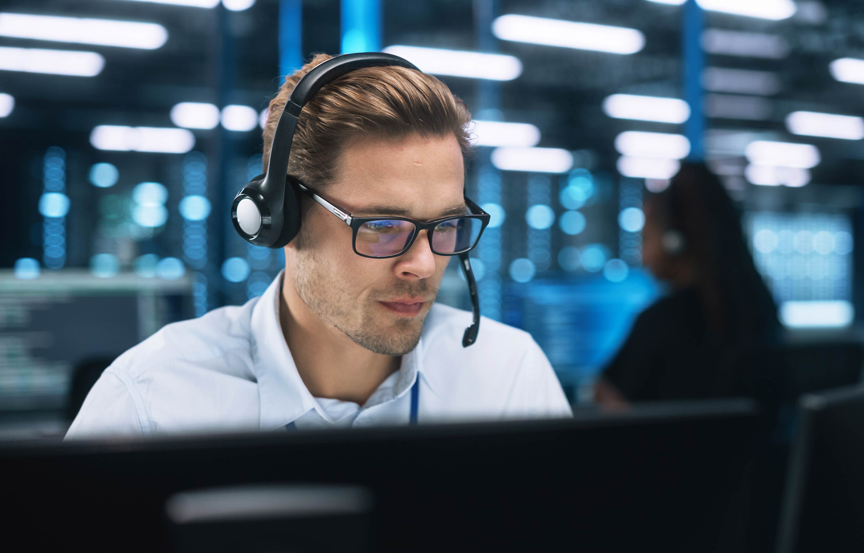 Ung man sitter med headset vid sin datorskärm.